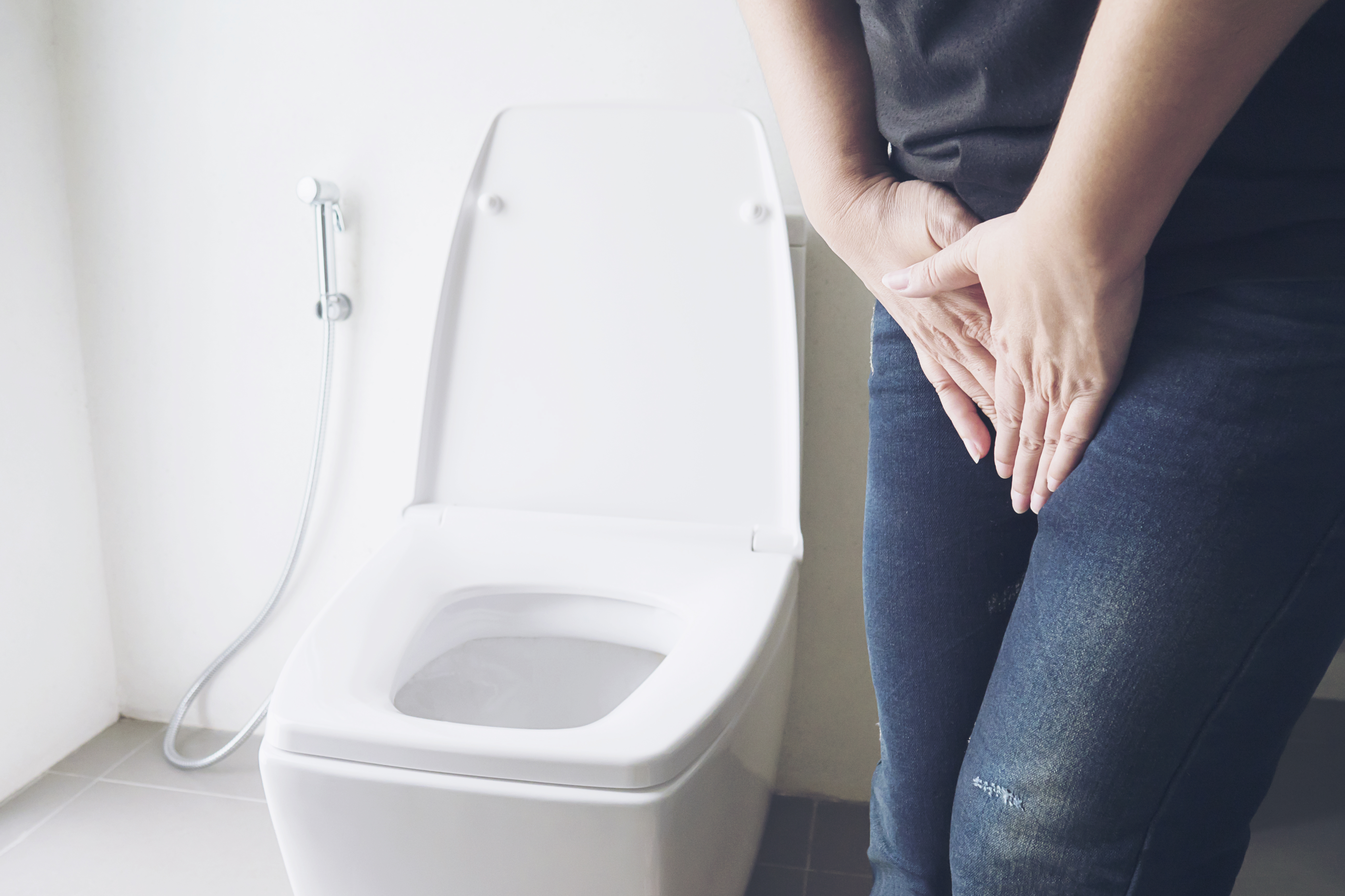 Woman holding hand near toilet bowl - health problem concept